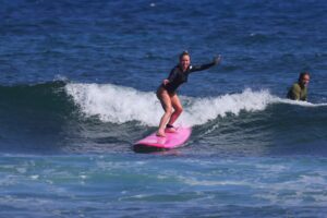 Beginner surfer riding a wave during a North Shore Oahu surf lesson.