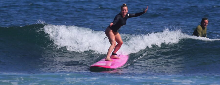 Beginner surfer riding a wave during a North Shore Oahu surf lesson.