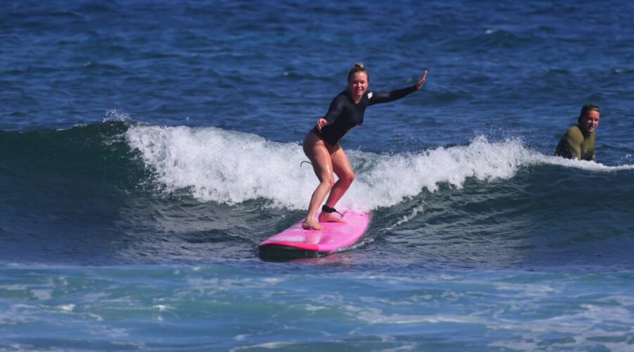 Beginner surfer riding a wave during a North Shore Oahu surf lesson.